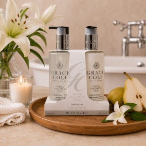 Coffret mains et corps poire & nectarine blanche Grace Cole, présenté sur un plateau en bois avec lys blancs, poire fraîche et bougie